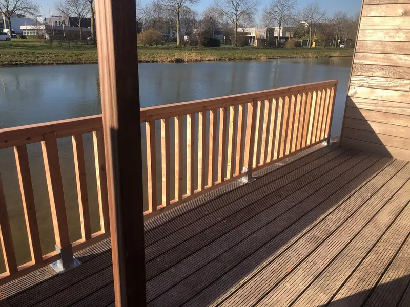 Dezelfde balustrade vanuit een andere hoek, met een houten staander op de voorgrond en een houten wand rechts